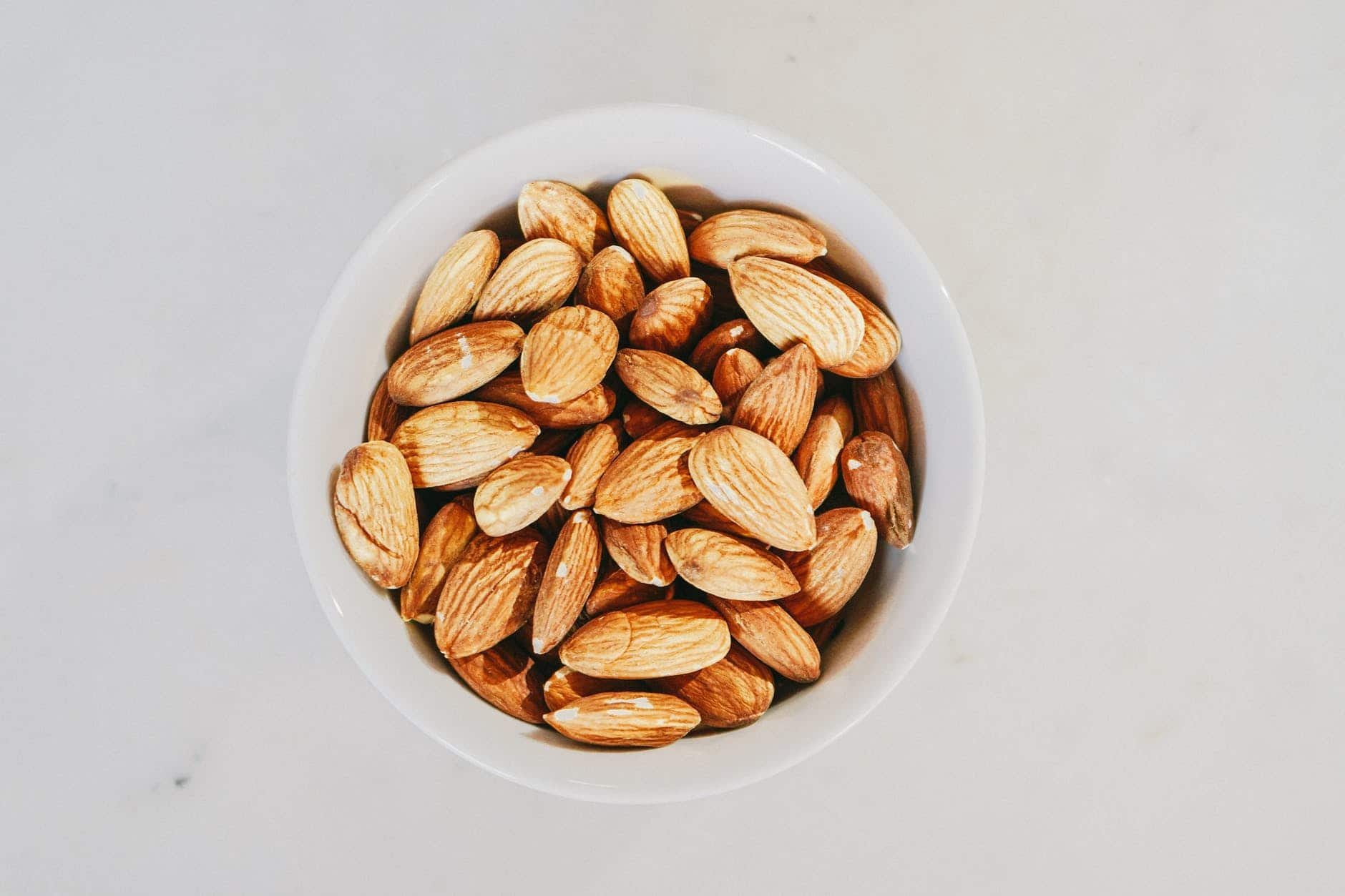 brown almond nuts on white ceramic bowl
