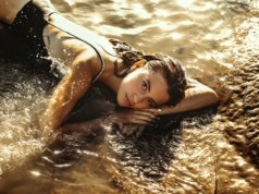 stylish model in swimsuit resting on shiny wavy ocean