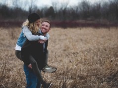 man carrying woman standing on the ground and surrounded by grass