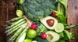 Assorted fresh green vegetables on rustic wooden table